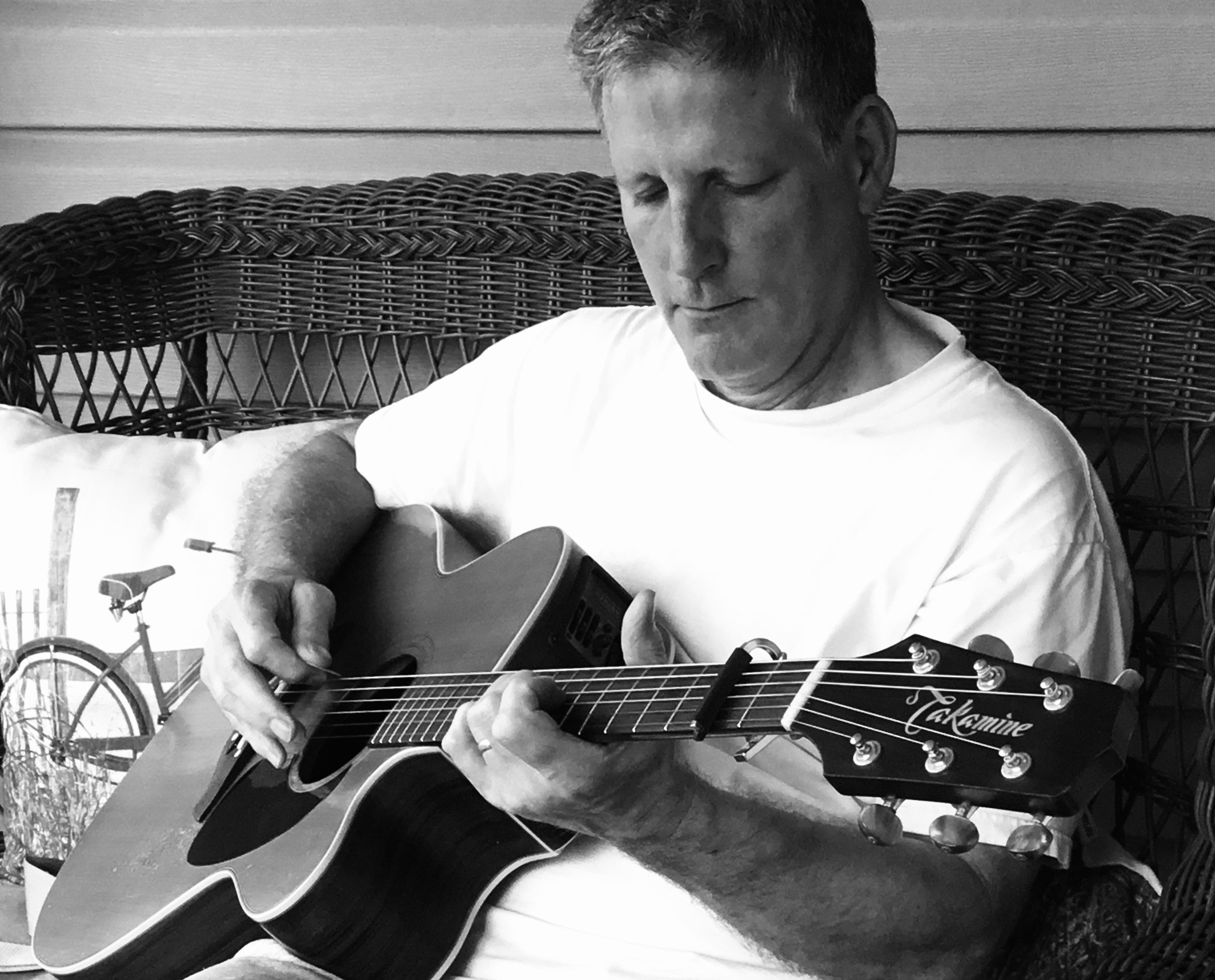 Andy Carignan seated playing acoustic guitar
